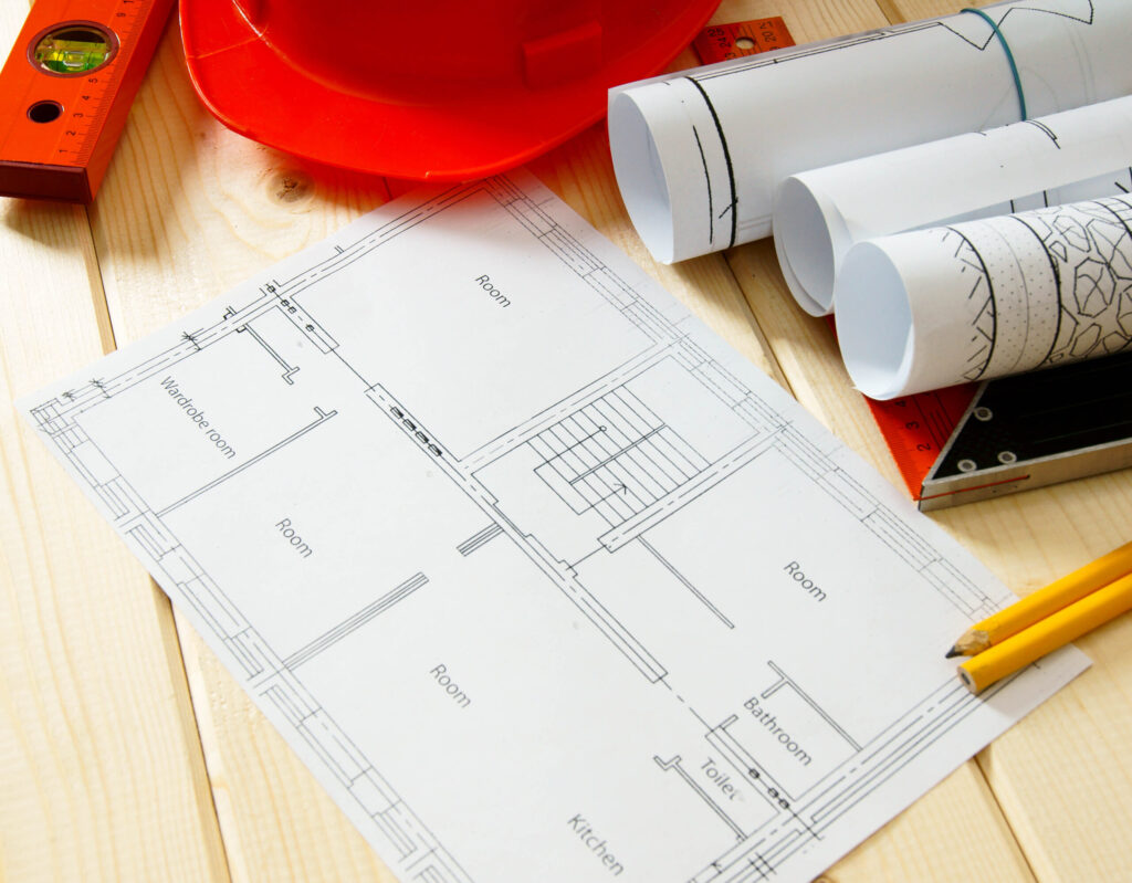 Repair work Drawings for building helmet pencils and others tools on wooden background - EZ Modern Homes Repair work Drawings for building helmet pencils and others tools on wooden background - EZ Modern Homes