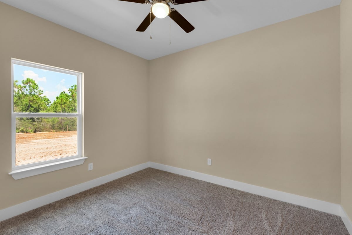 carpeted bedroom with window view in Pensacola FL custom home by EZ Modern Homes The Poderosa-optimized