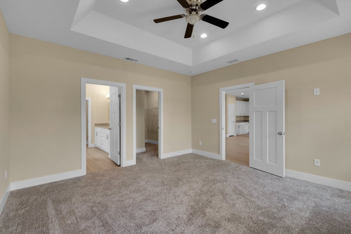 large bedroom with tray ceiling and ceiling fan in Pensacola FL custom home by EZ Modern Homes The Poderosa-optimized