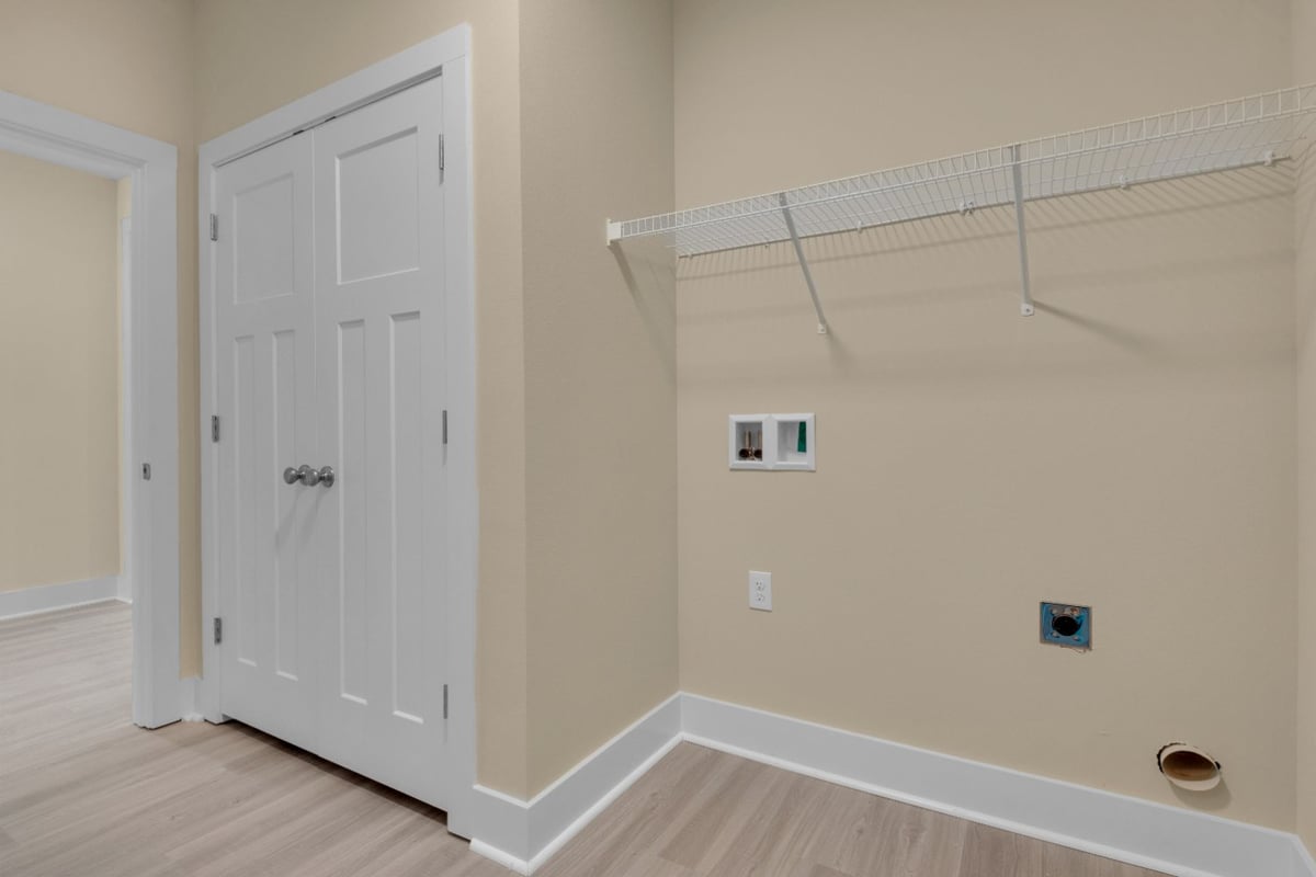 laundry room with hookups and storage shelving in The Poderosa custom home by EZ Modern Homes Pensacola, FL-optimized