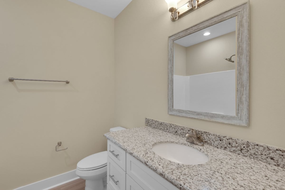 modern bathroom with granite vanity and framed mirror in The Poderosa custom home by EZ Modern Homes Pensacola, FL-optimized