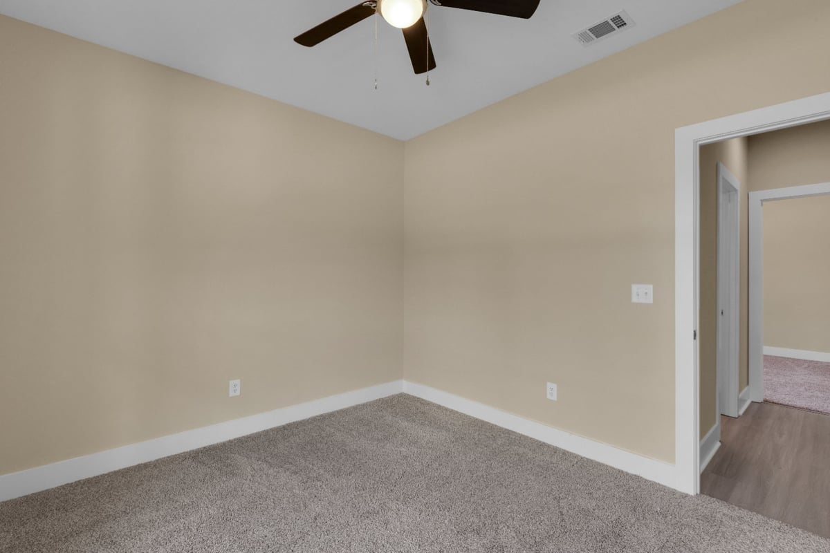 neutral bedroom with doorway access and ceiling fan in The Poderosa custom home by EZ Modern Homes Pensacola, FL-optimized
