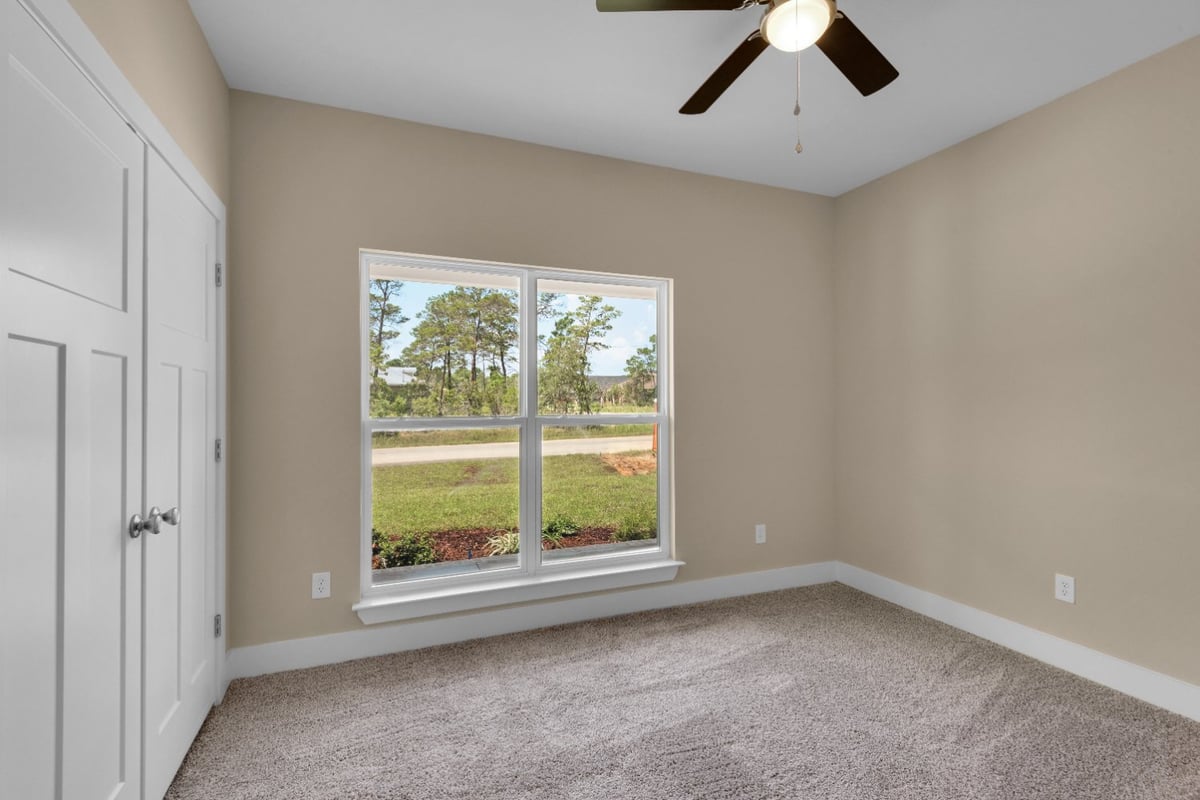 spacious bedroom with large window and ceiling fan in The Poderosa custom home by EZ Modern Homes Pensacola, FL-optimized
