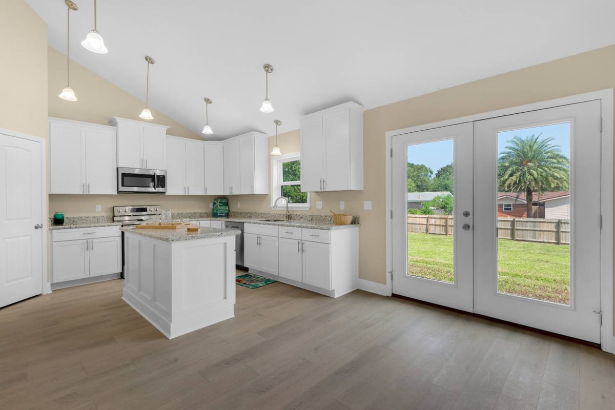 Kitchen and dining area with glass doors to backyard in Pensacola FL custom home The Pins-optimized