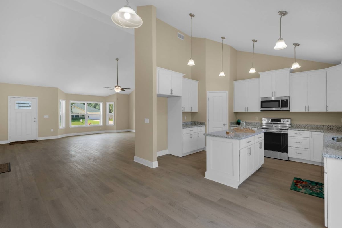 Open kitchen and living area with island in custom home by EZ Modern Homes Pensacola FL The Pins-optimized