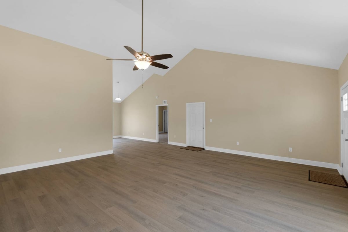 Open living room with ceiling fan and neutral finishes in Pensacola FL custom home The Pins-optimized