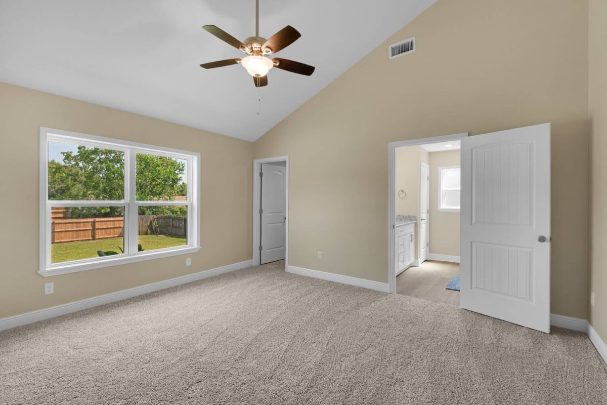 Spacious carpeted bedroom with vaulted ceiling and ceiling fan in custom home by EZ Modern Homes in Pensacola, FL The Pins-optimized