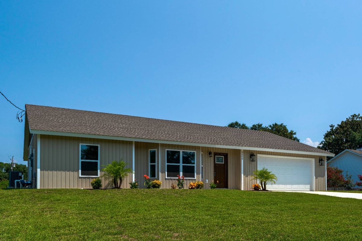 Wide front view of custom home with manicured lawn by EZ Modern Homes Pensacola FL The Pins-optimized