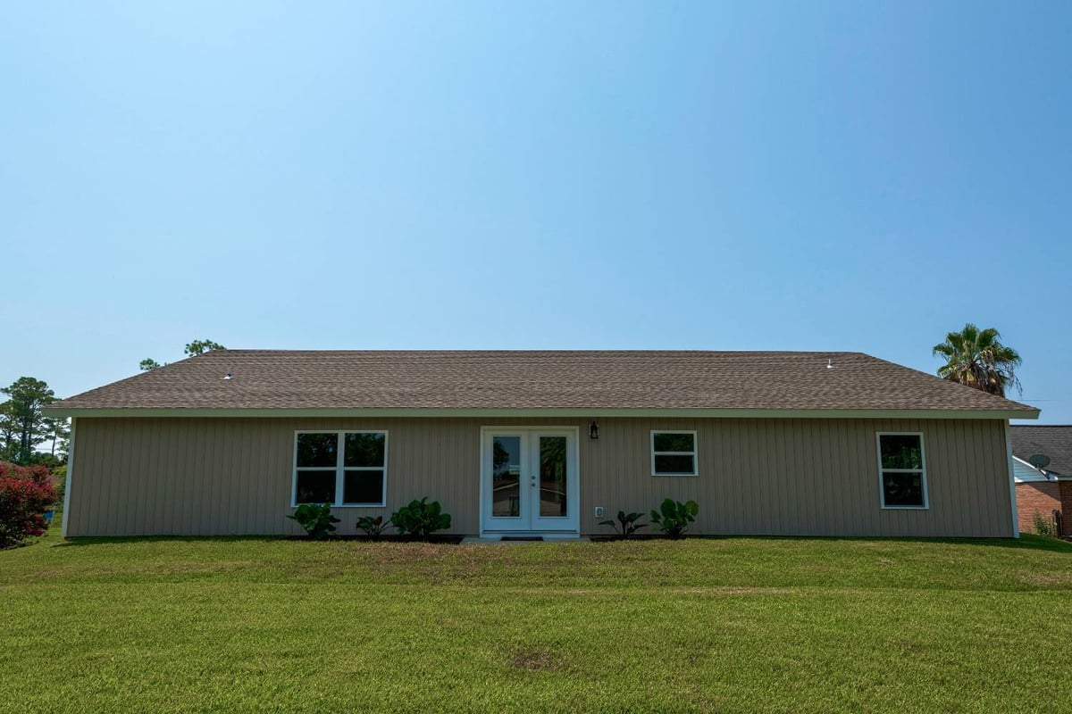 backyard view of custom home exterior with patio doors and lawn in Pensacola, FL by EZ Modern Homes-optimized