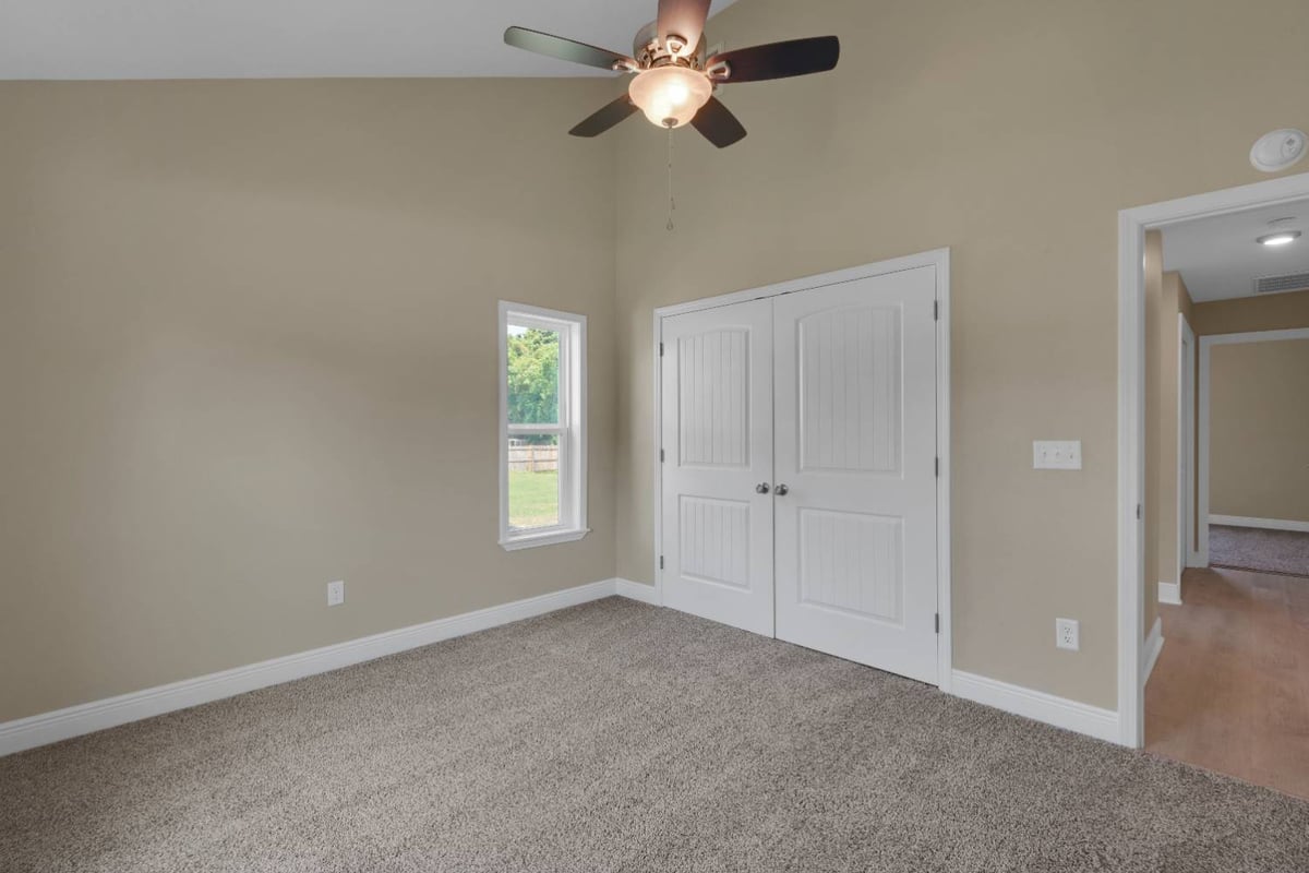 bedroom with double closet doors and ceiling fan in custom home by EZ Modern Homes in Pensacola, FL-optimized