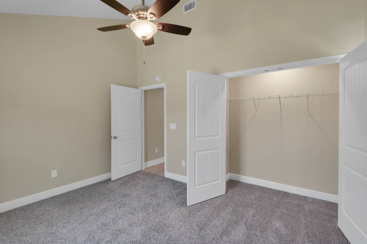 bedroom with open closet and ceiling fan in custom home by EZ Modern Homes in Pensacola, FL-optimized
