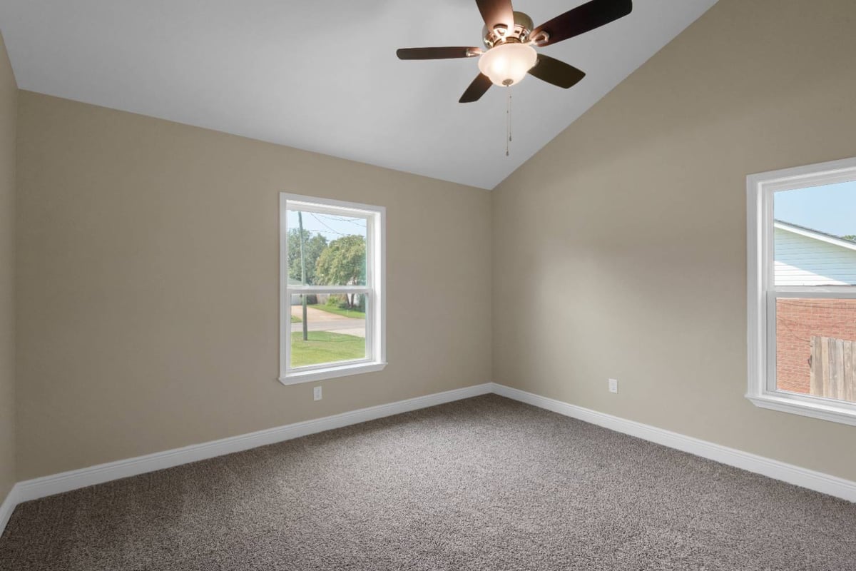 carpeted bedroom with ceiling fan and dual windows in custom home by EZ Modern Homes in Pensacola, FL-optimized