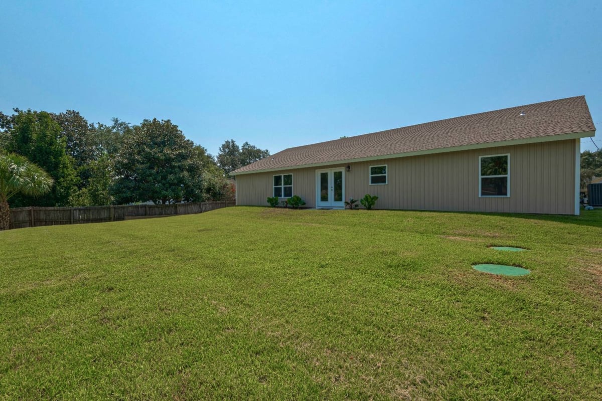expansive backyard lawn with rear view of custom home in Pensacola, FL by EZ Modern Homes-optimized