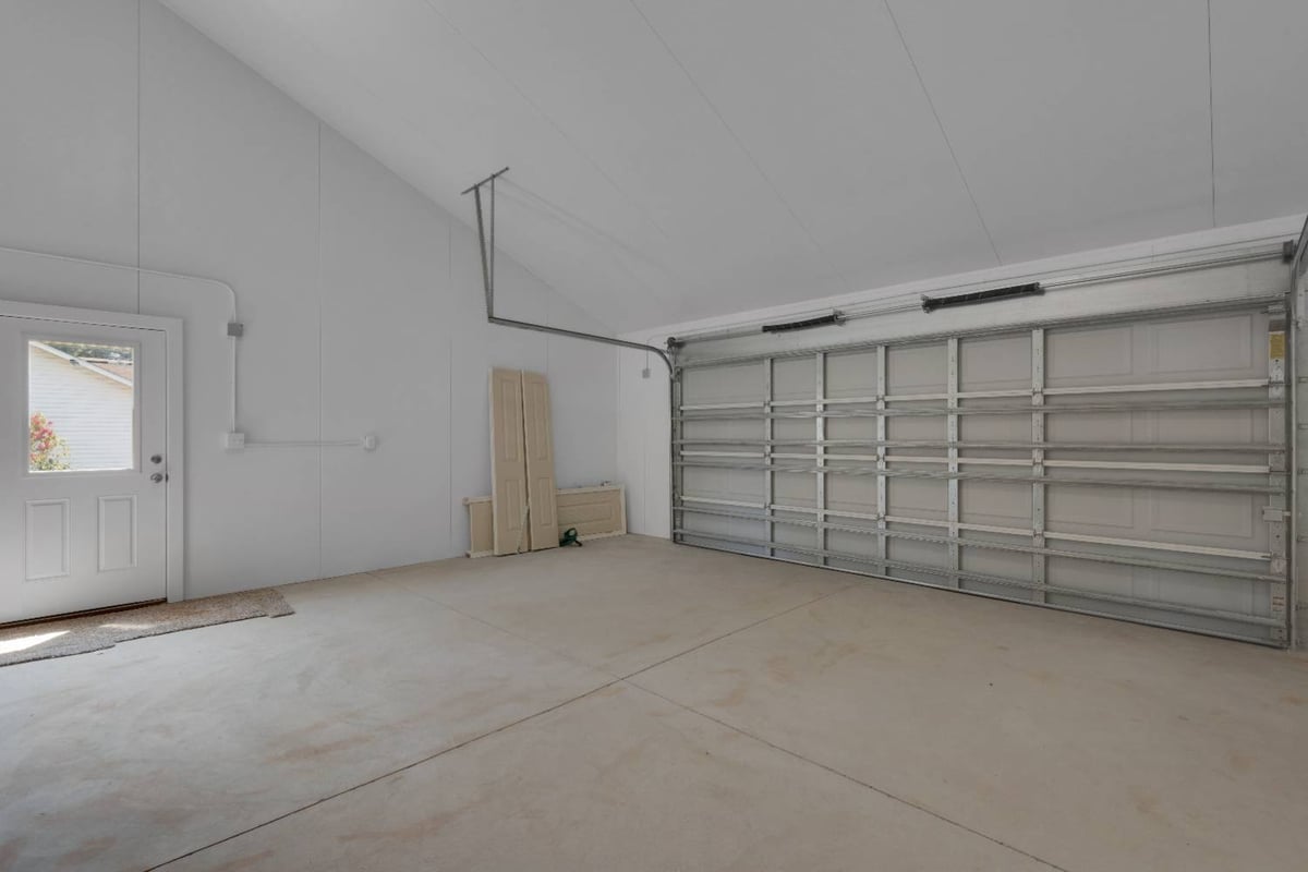 spacious garage interior with overhead door and side entry in Pensacola custom home by EZ Modern Homes-optimized
