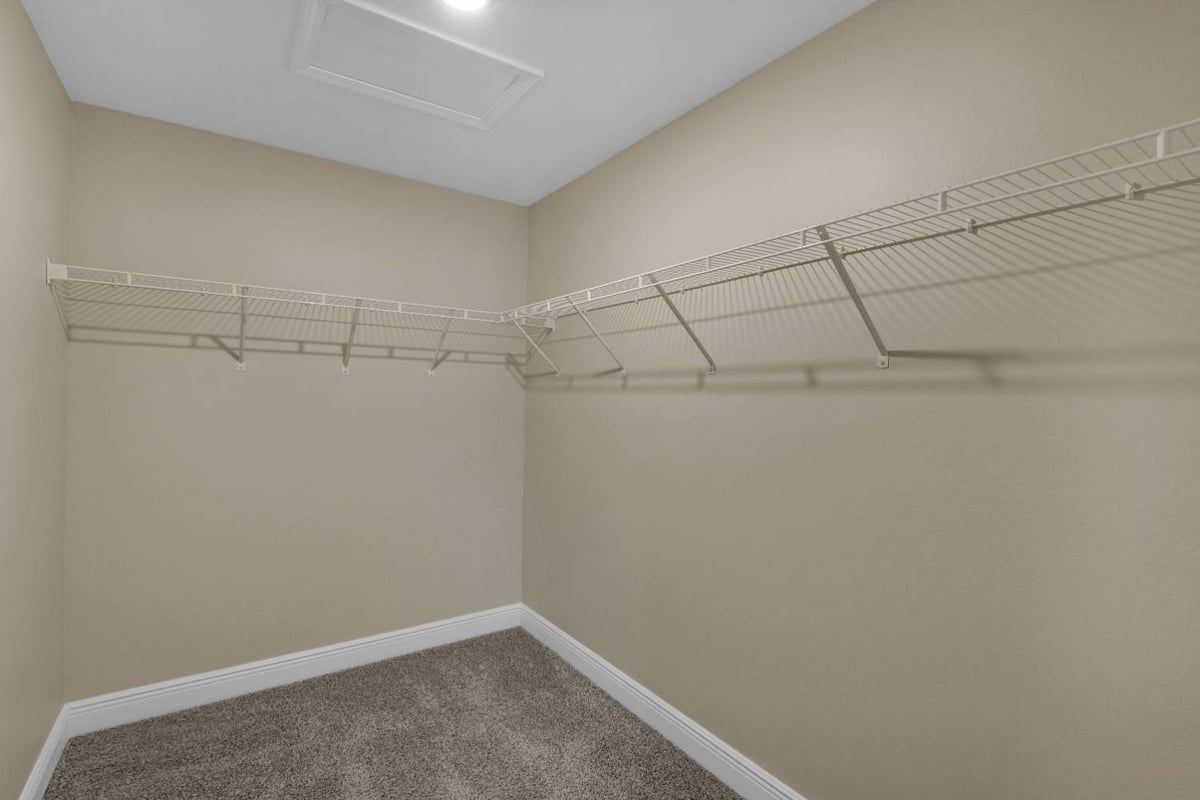 walk-in closet with wire shelving and carpet flooring in custom home by EZ Modern Homes in Pensacola, FL-optimized