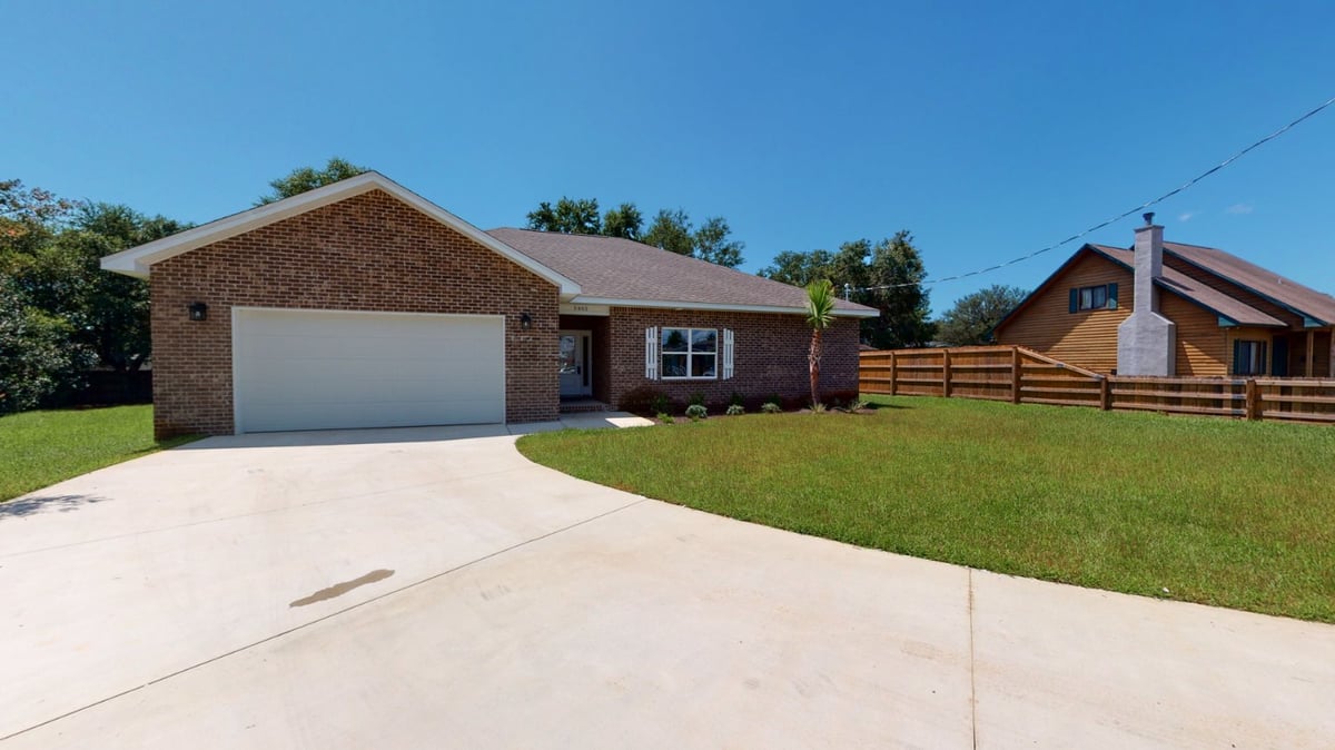 Closer exterior view of a custom home by EZ Modern Homes in Pensacola, FL highlighting garage, entryway, and front landscaping.-optimized