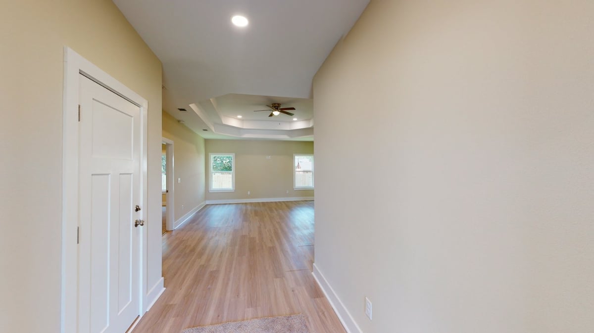Interior hallway leading to open living area in a custom home by EZ Modern Homes in Pensacola, FL with wood flooring.-optimized
