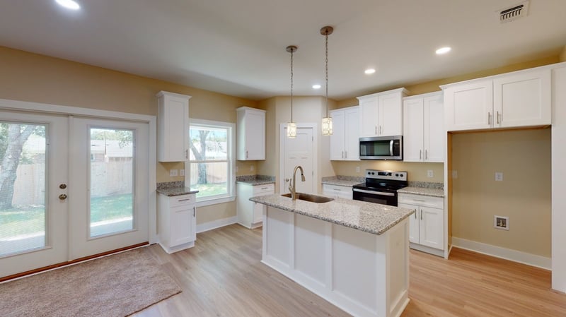 Modern kitchen with island and white cabinets in a custom home by EZ Modern Homes in Pensacola, FL.-optimized