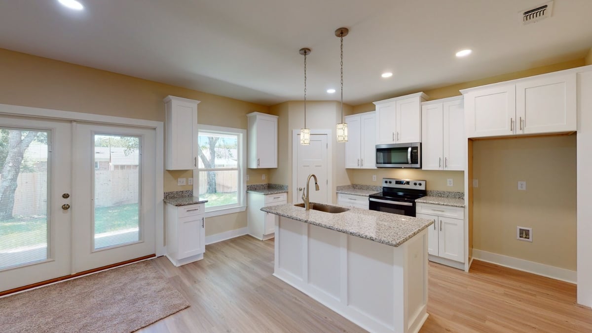 Modern kitchen with island and white cabinets in a custom home by EZ Modern Homes in Pensacola, FL.-optimized