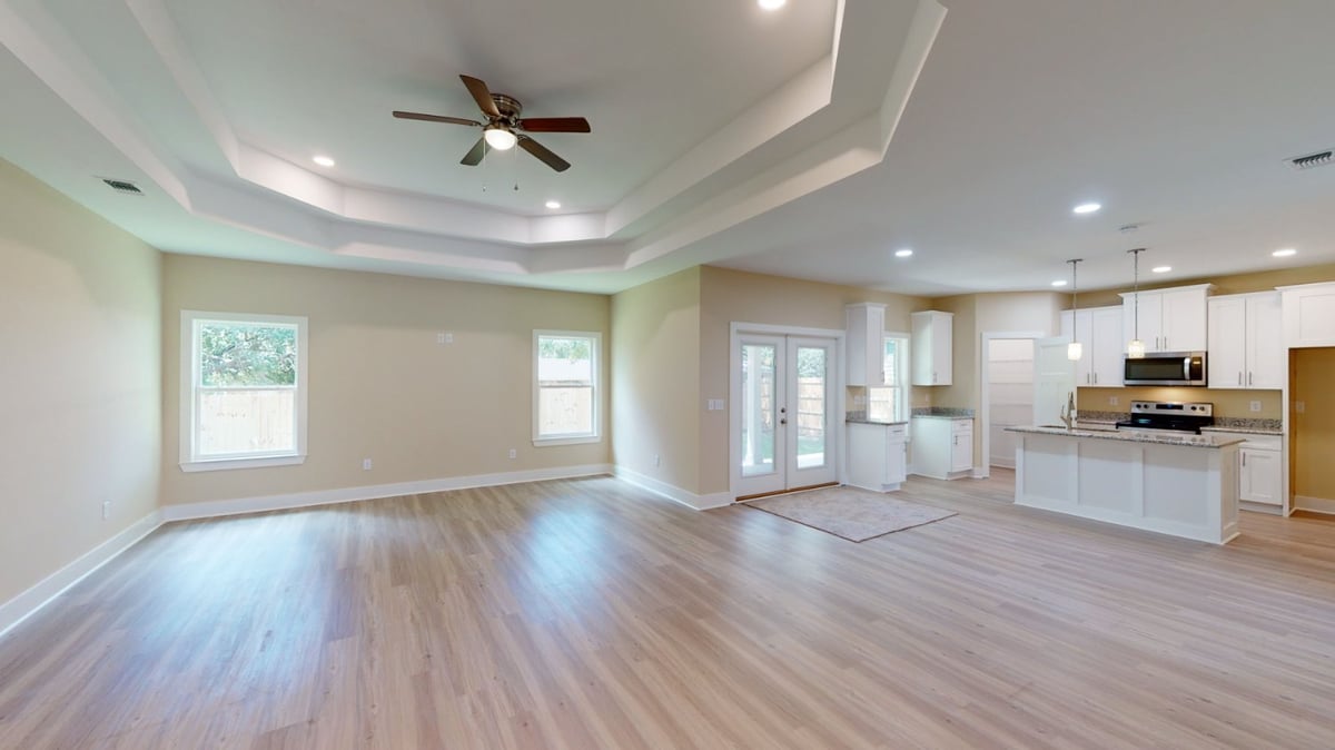 Spacious living room and kitchen of The Abilene custom home in Pensacola, FL by EZ Modern Homes with modern finishes.-optimized