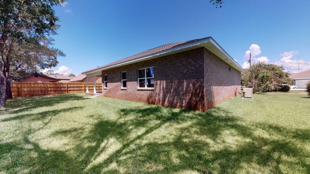 backyard lawn with wooden fence and brick home by EZ Modern Homes custom home Pensacola FL The Abilene-optimized-optimized