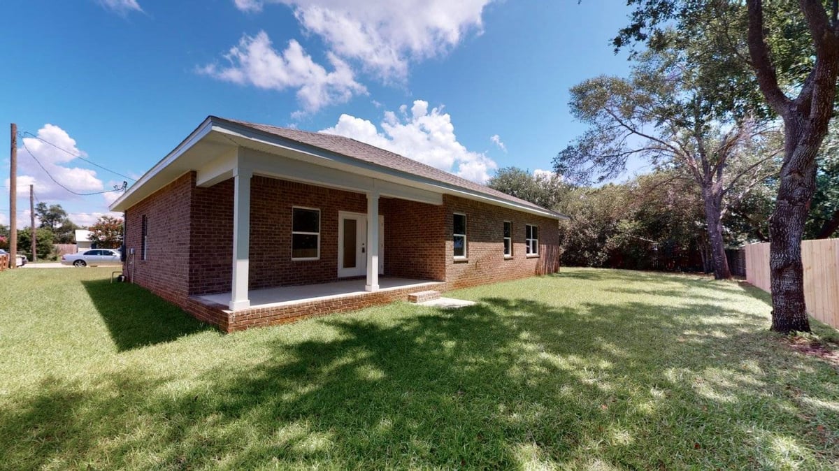 backyard view of brick home and patio in EZ Modern Homes Pensacola FL custom home The Abilene-optimized-optimized