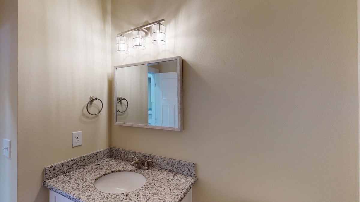 bathroom sink with granite counter and wall mirror in EZ Modern Homes custom home Pensacola FL The Abilene-optimized
