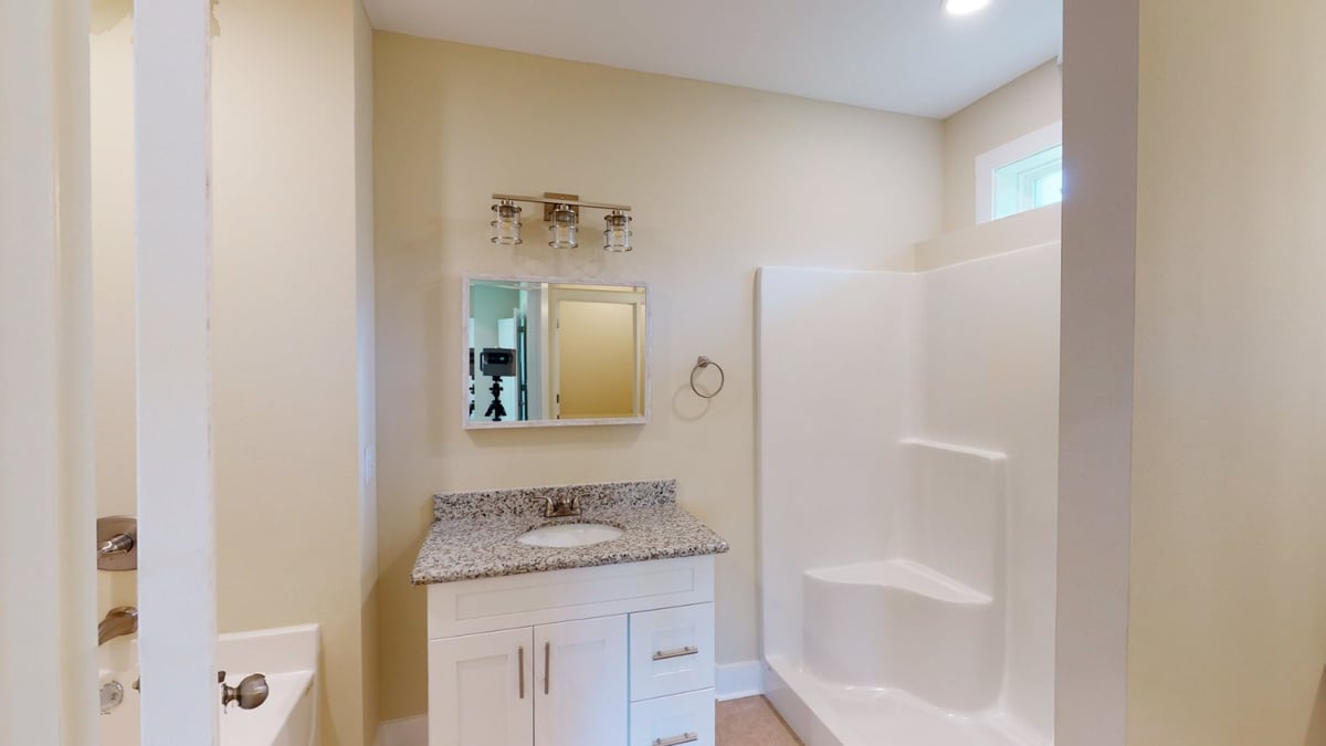 bathroom vanity with granite countertop and shower in custom home by EZ Modern Homes Pensacola, FL-optimized