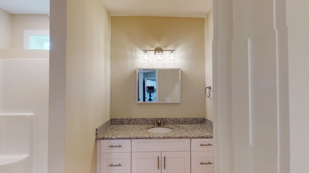 bathroom vanity with mirror and lighting in custom home by EZ Modern Homes Pensacola, FL-optimized