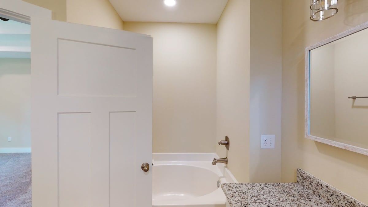 bathroom with tub shower combo and granite vanity in custom home by EZ Modern Homes Pensacola, FL-optimized
