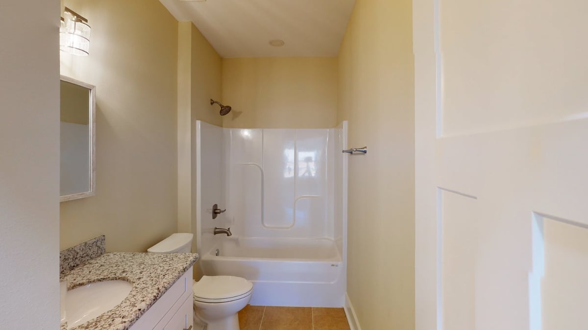 bathroom with tub shower combo and toilet in custom home by EZ Modern Homes Pensacola, FL-optimized