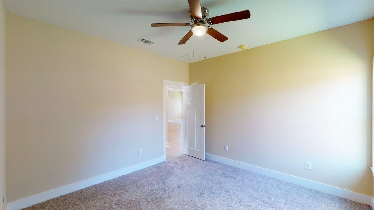 bedroom with ceiling fan and open doorway in custom home by EZ Modern Homes Pensacola, FL-optimized