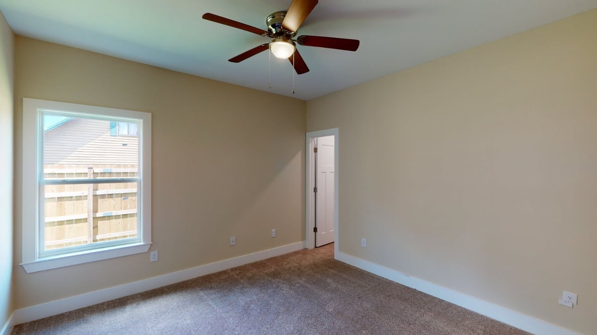 bedroom with ceiling fan and window in custom home by EZ Modern Homes Pensacola, FL-optimized