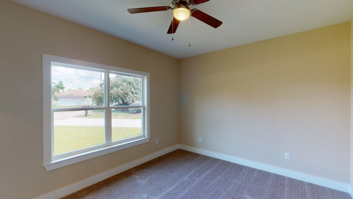 bright bedroom with large window and ceiling fan in EZ Modern Homes custom home Pensacola FL The Abilene-optimized