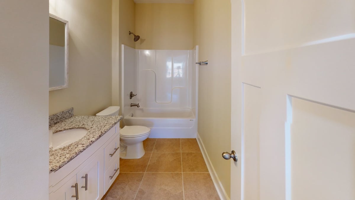 clean bathroom design with granite counter and bathtub in Pensacola, FL custom home by EZ Modern Homes-optimized