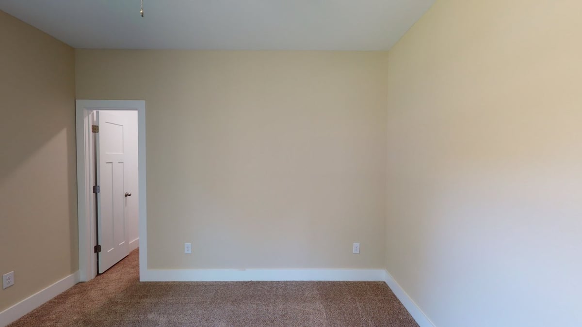 empty bedroom with doorway and neutral walls in custom home by EZ Modern Homes Pensacola, FL-optimized