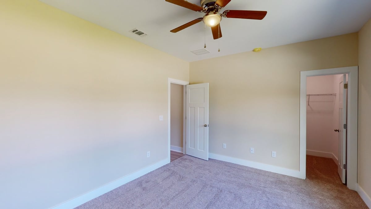 neutral bedroom with ceiling fan and closet space by EZ Modern Homes custom home Pensacola FL The Abilene-optimized