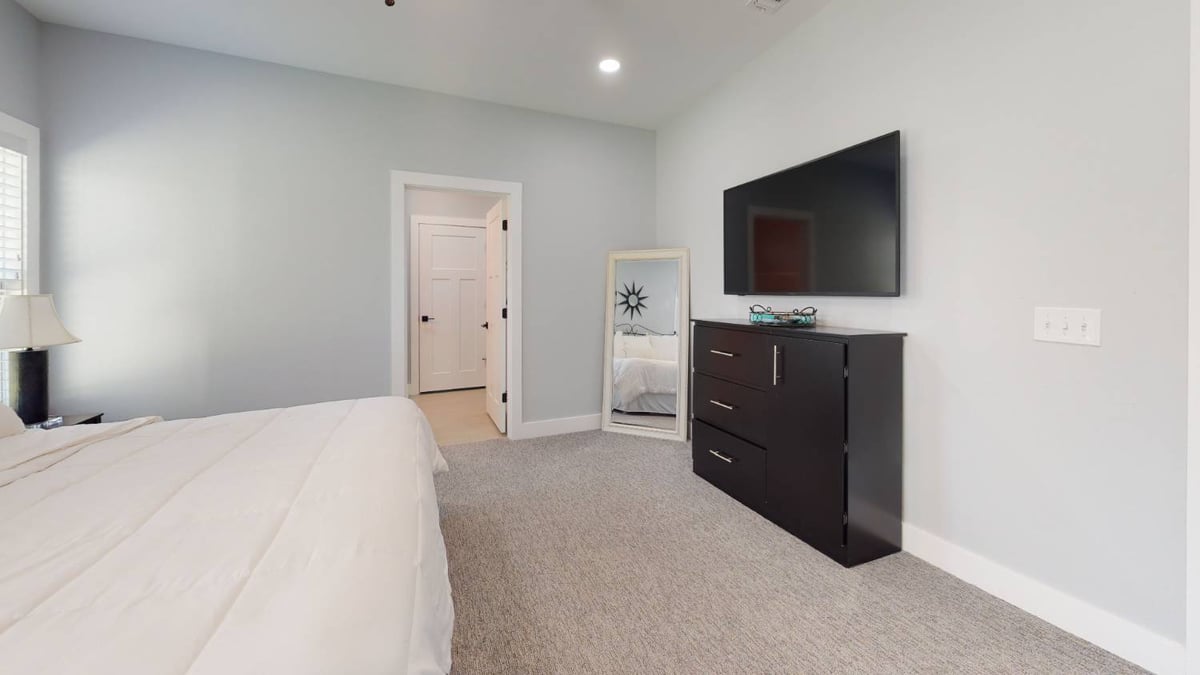 bedroom with bed, dresser, and mounted TV in The Lafon custom home by EZ Modern Homes in Pensacola, FL-optimized
