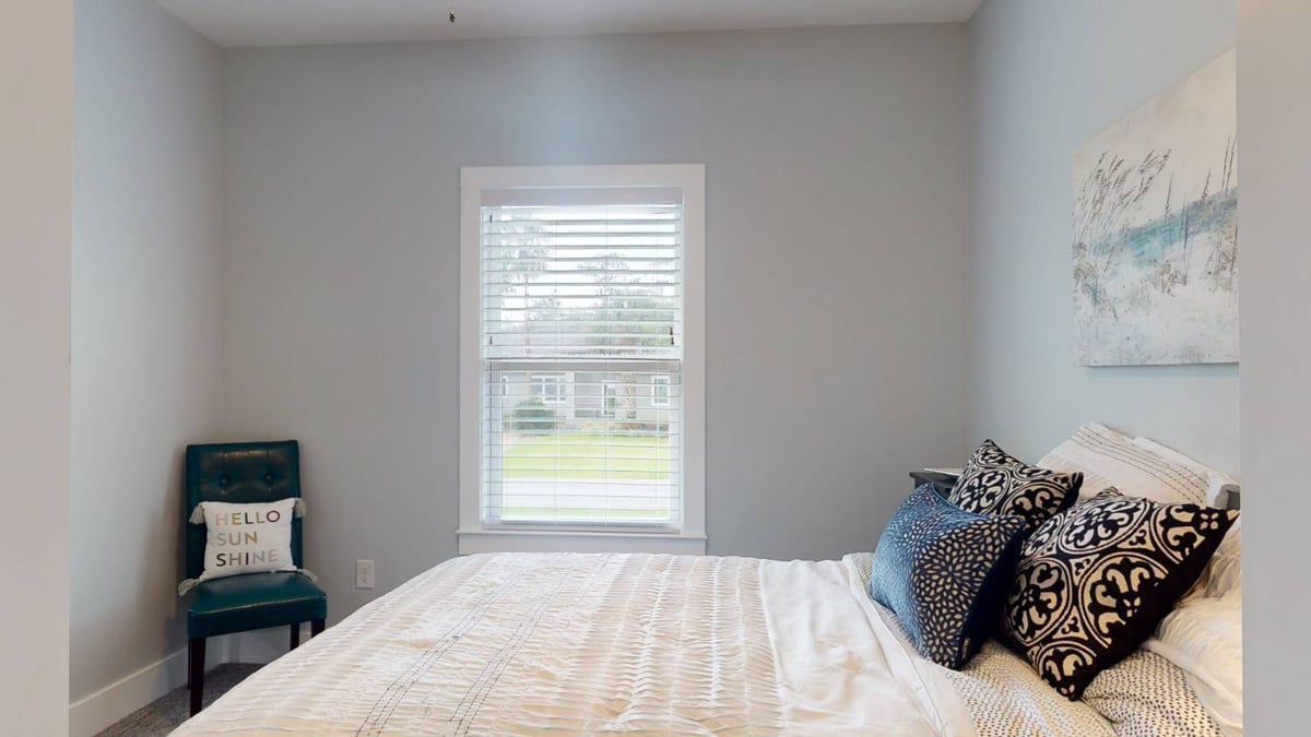 bedroom with window view and decorative pillows by EZ Modern Homes custom home in Pensacola FL The Lafon-optimized