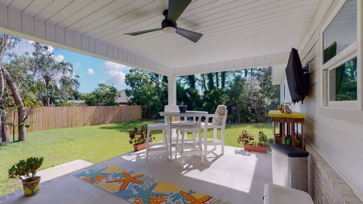 covered backyard patio with outdoor seating and ceiling fan by EZ Modern Homes custom home-optimized