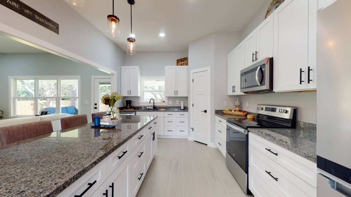 galley-style kitchen with large island and modern appliances in The Lafon custom home by EZ Modern Homes in Pensacola, FL-optimized