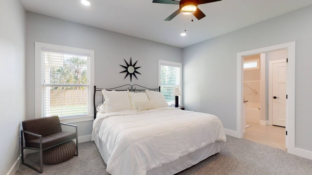 master bedroom with neutral tones and large windows in The Lafon custom home by EZ Modern Homes in Pensacola, FL-optimized