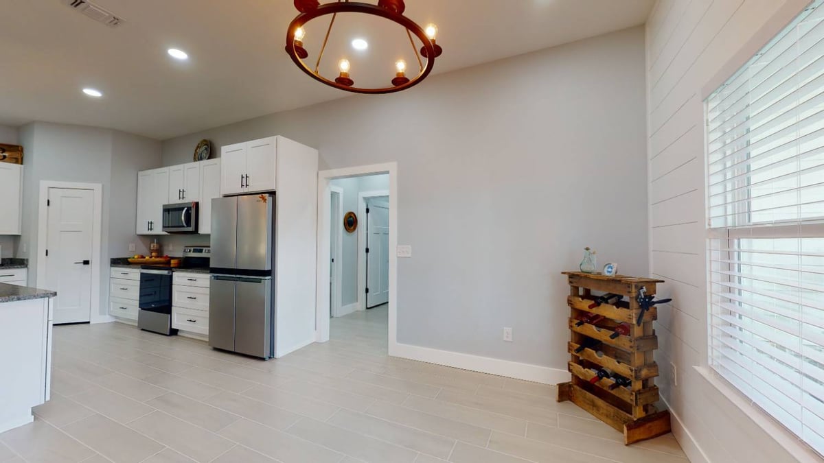 modern kitchen with island and adjacent hallway in The Lafon custom home by EZ Modern Homes in Pensacola, FL-optimized