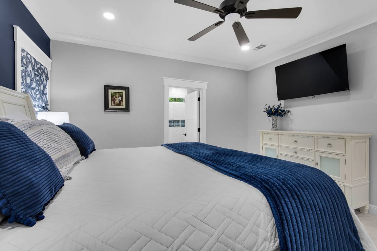 Bedroom view toward dresser and mounted TV in The Lafon custom home by EZ Modern Homes Pensacola, FL-optimized