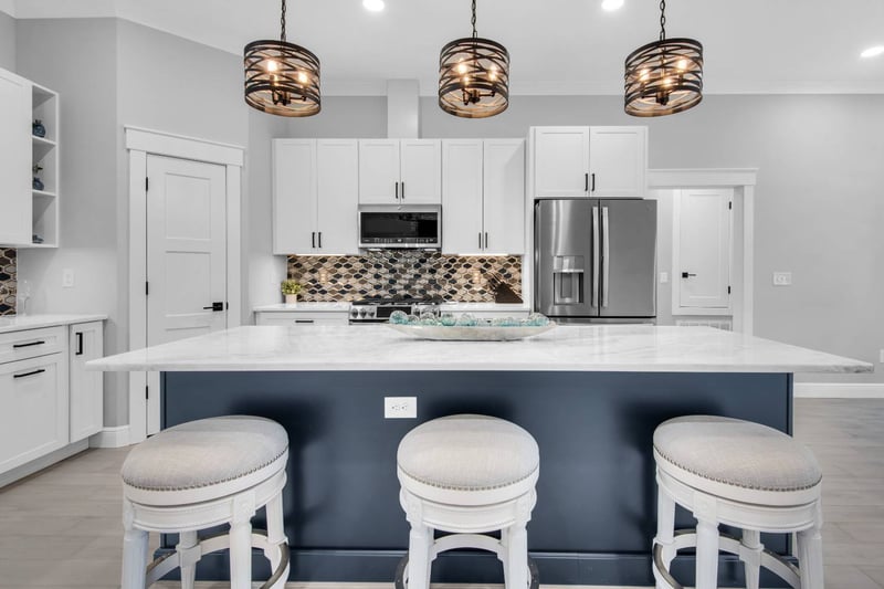 Front view of large kitchen island with seating and pendant lights in The Lafon custom home by EZ Modern Homes Pensacola, FL-optimized