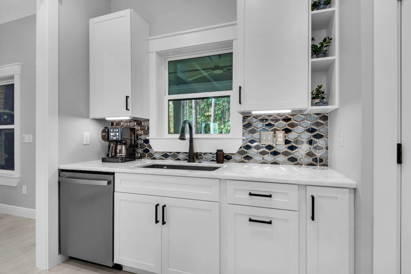 Kitchen sink area with window and tile backsplash in The Lafon custom home by EZ Modern Homes Pensacola, FL-optimized