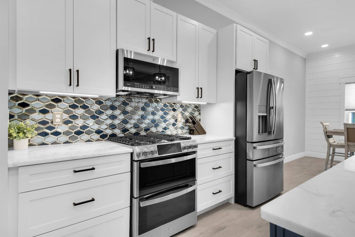 Kitchen stove and cabinetry with decorative backsplash in The Lafon custom home by EZ Modern Homes Pensacola, FL-optimized