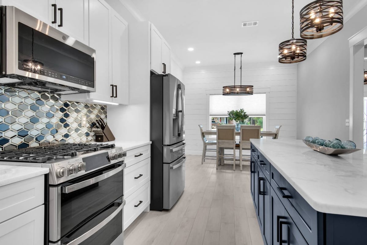 Kitchen view toward dining area with island and pendant lights in The Lafon custom home by EZ Modern Homes Pensacola, FL-optimized