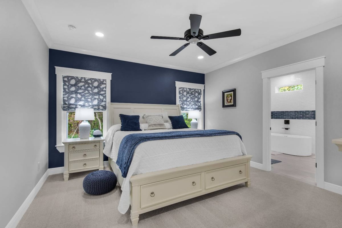 Master bedroom with blue accent wall and modern decor in The Lafon custom home by EZ Modern Homes Pensacola, FL-optimized