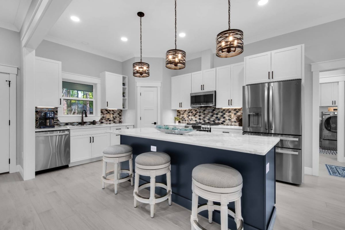 Modern kitchen with large island, pendant lighting, and white cabinetry in The Lafon custom home by EZ Modern Homes in Pensacola-optimized